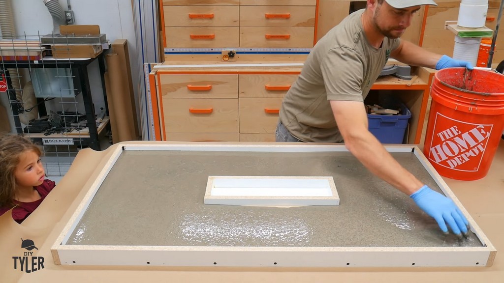 man smoothing out concrete mix in tabletop mold