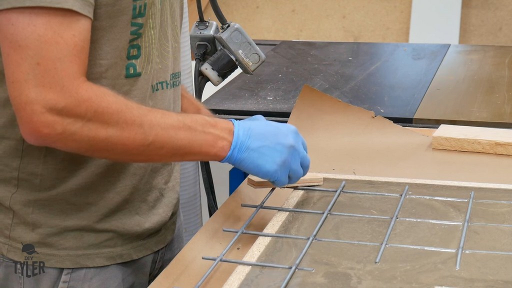 man tying scrap wood to corner of galvanized fencing piece