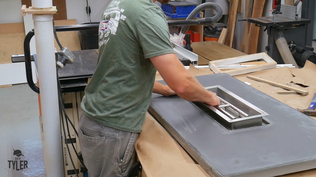 man installing fire pan into DIY deck fire table slab