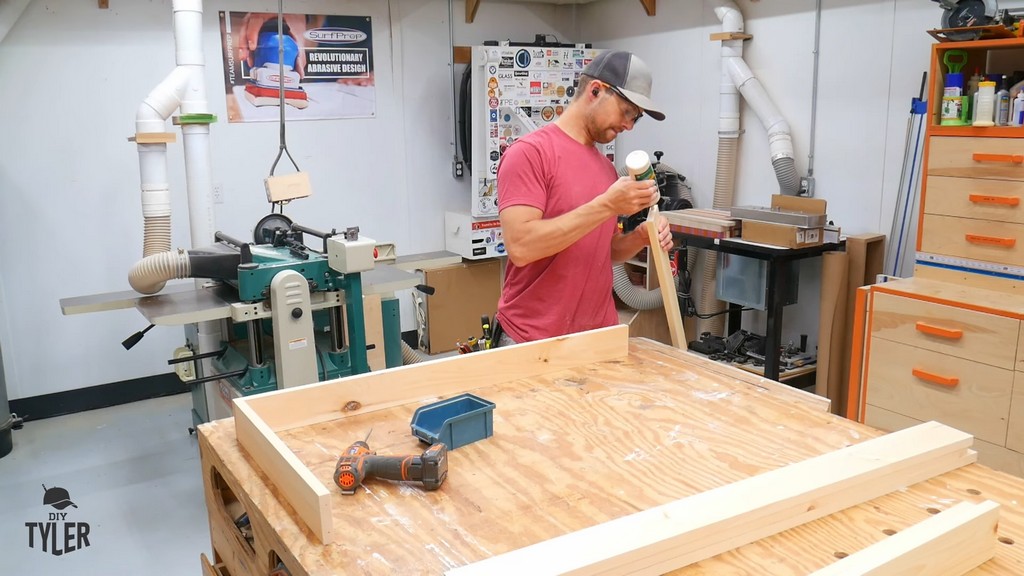 man applying wood glue to pine board frame piece