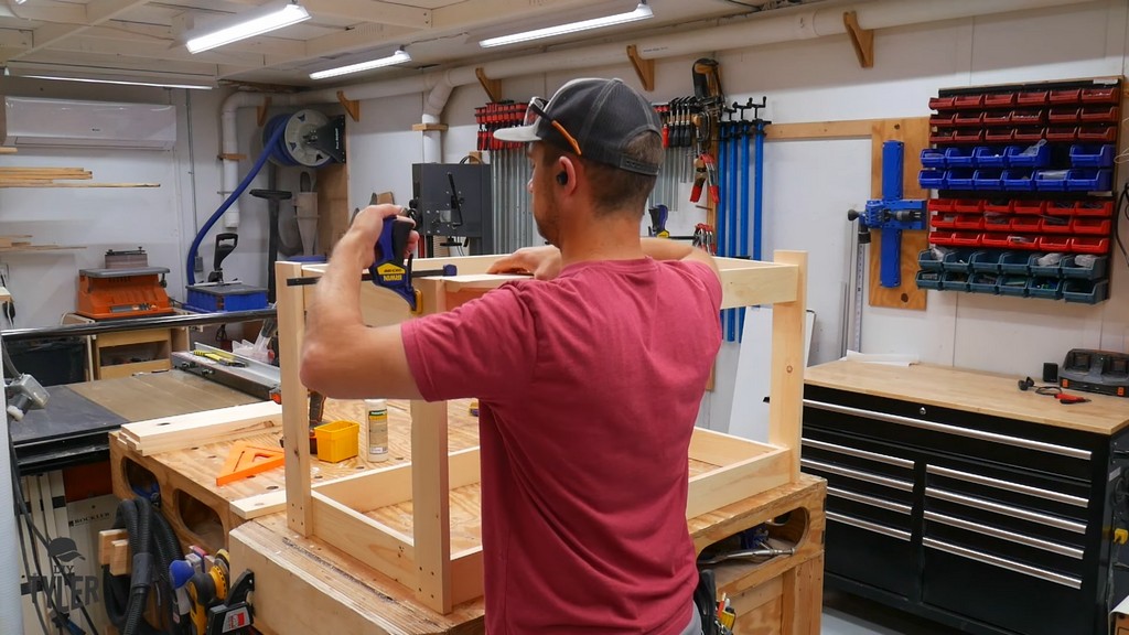 man clamping glued pinewood pieces together for table frame