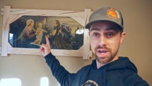 man pointing to framed portrait of Holy Family