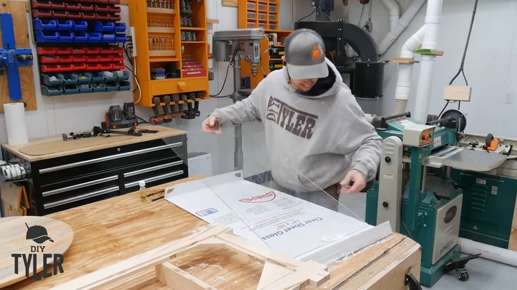 man holding sheet of glass for square picture frame