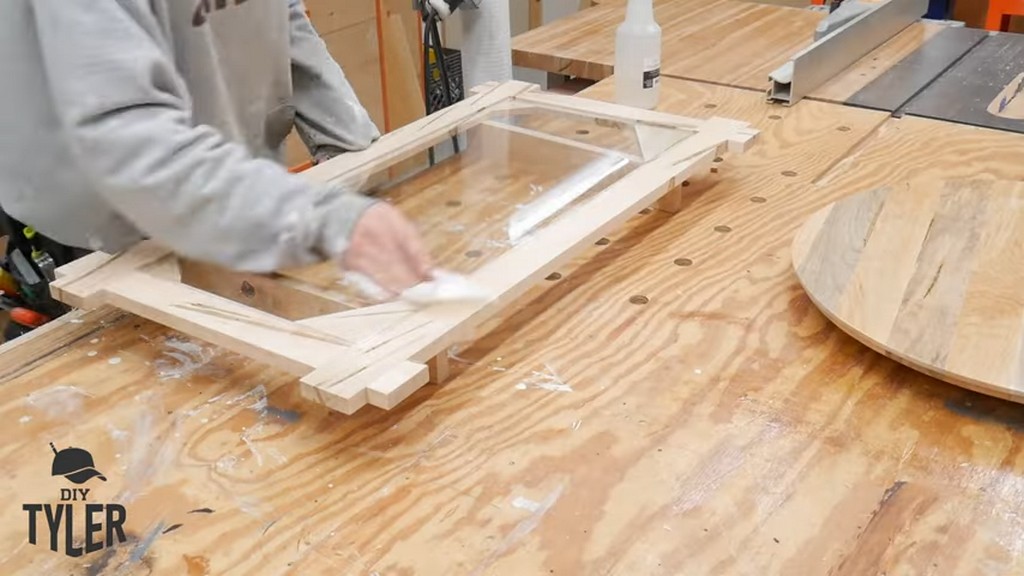 man wiping down sheet of glass for square picture frame