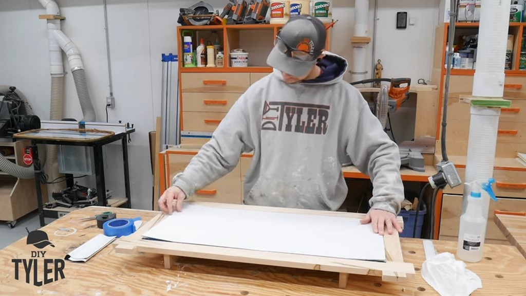 man applying backing board to square picture frame