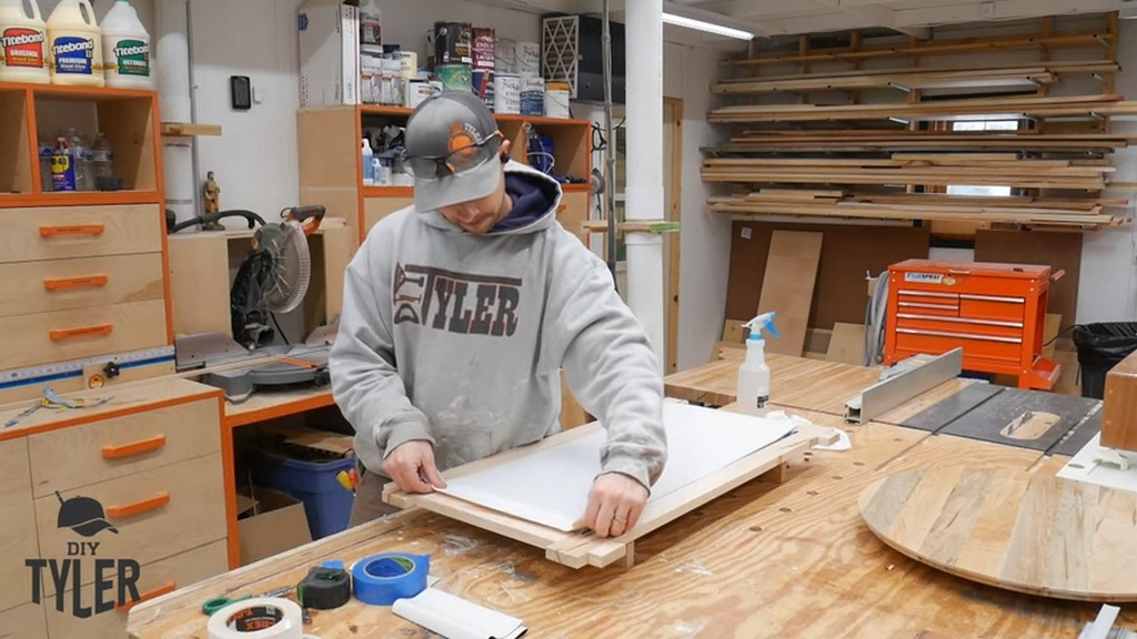 man applying T-rex Tape to backing board for square picture frame
