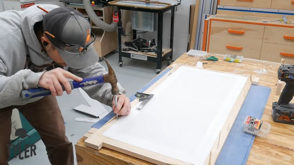 man affixing sawtooth hangers to square picture frame