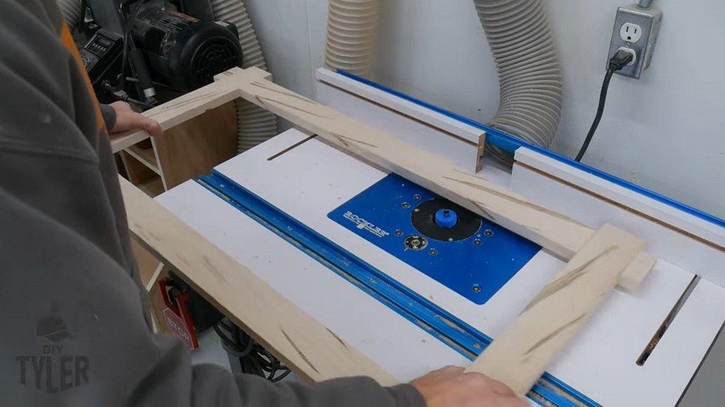 man using rabbiting router bit on square picture frame