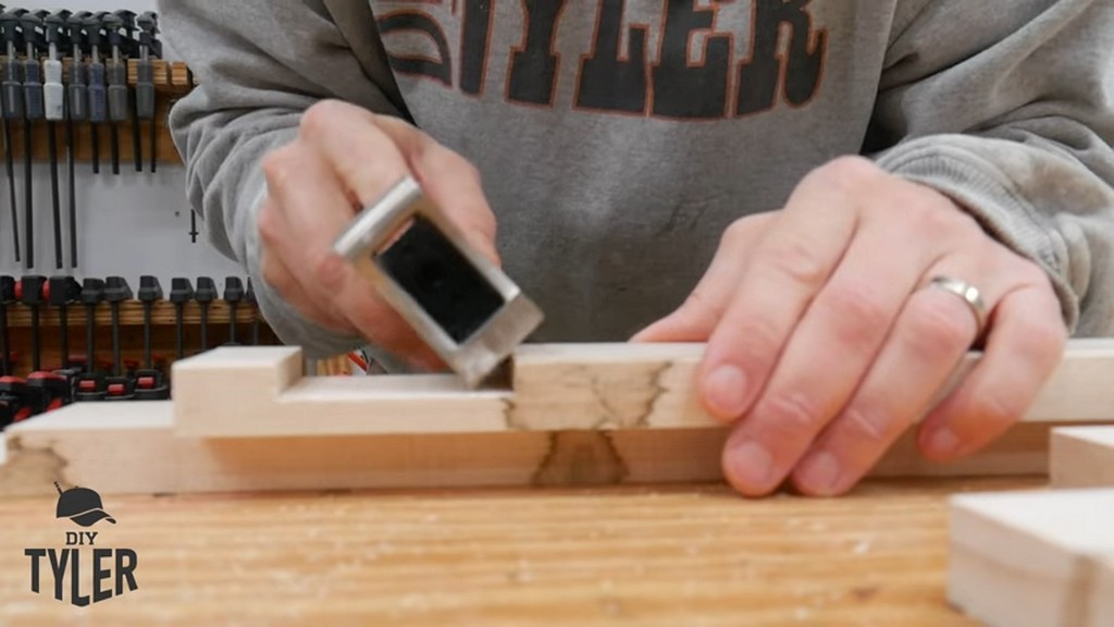 man using hand planer on edge of milled board half-lap joint