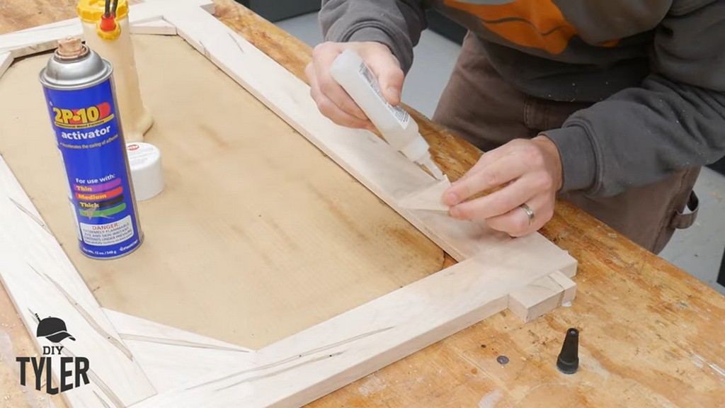 man applying CA glue to corner piece of square picture frame