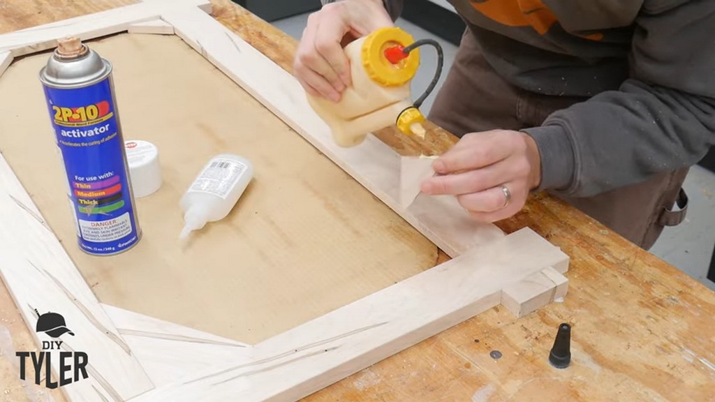 man applying wood glue to corner piece for square picture frame