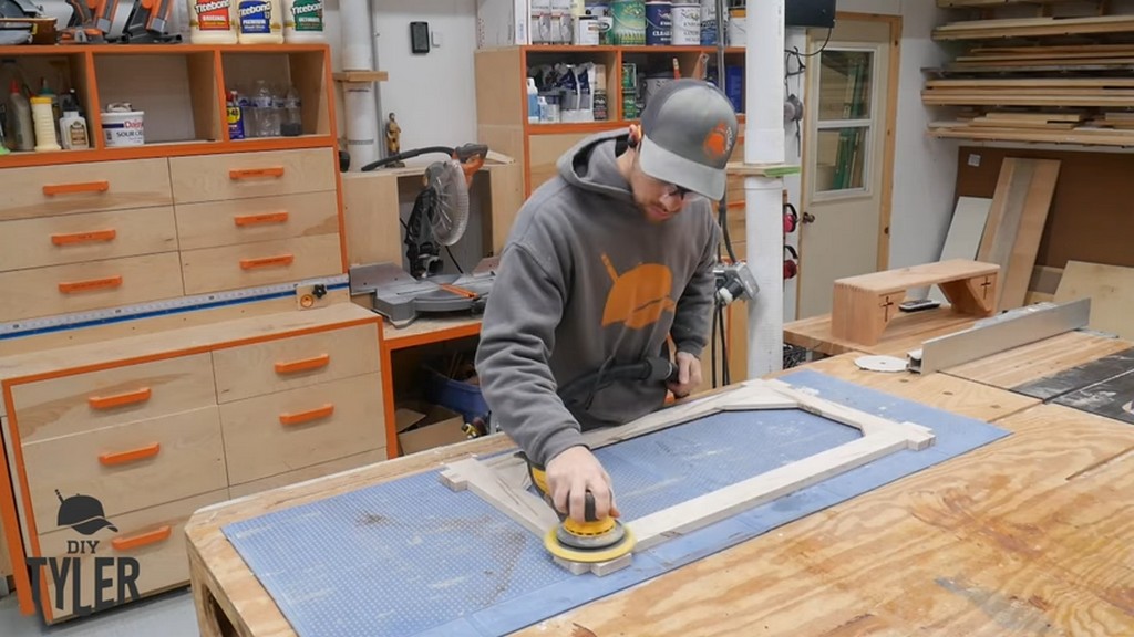man sanding constructed square picture frame