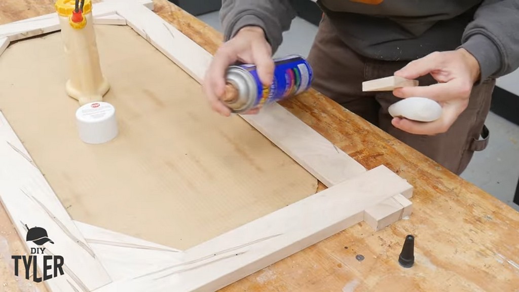 man applying activator spray to back of square picture frame