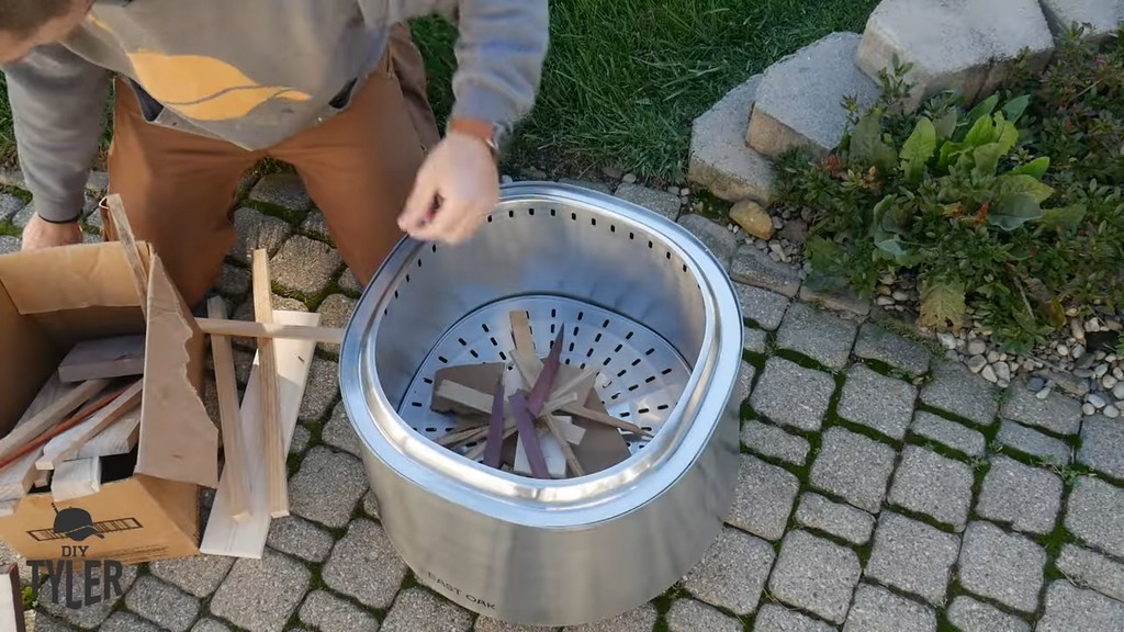 man putting wood scraps into East Oak smokeless firepit