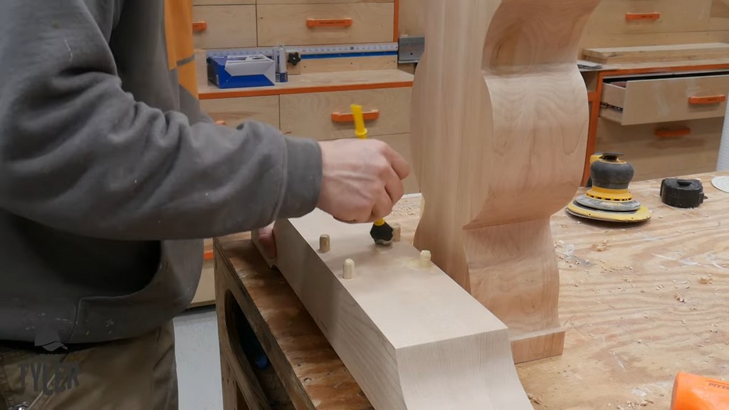man applying wood glue to dowels for pedestal piece