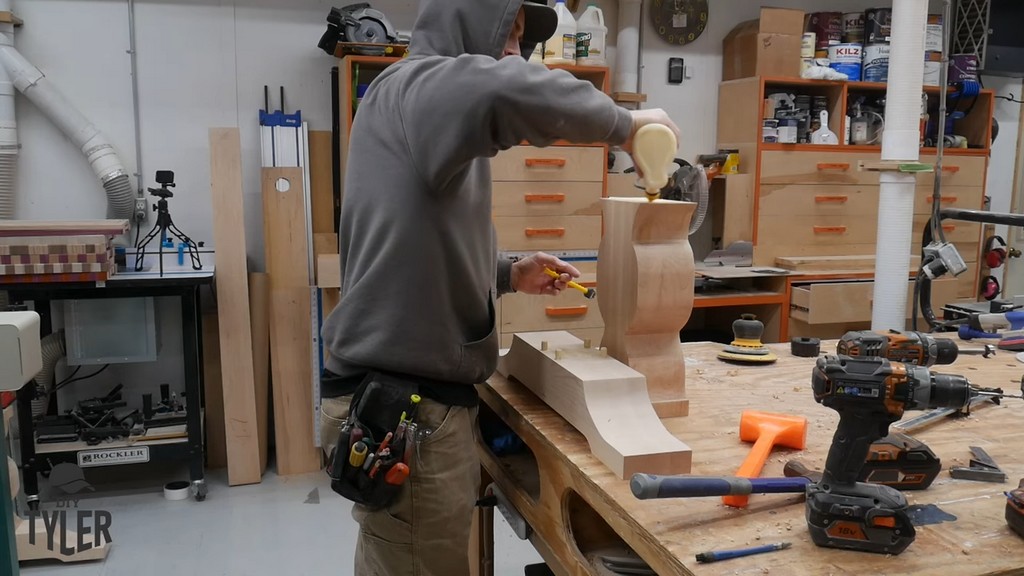 man applying wood glue to dowel holes for vertical pedestal piece