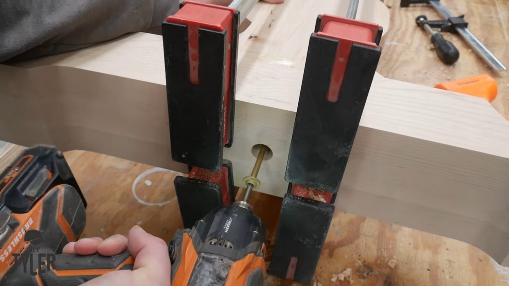 man drilling structural screw into wooden pedestal