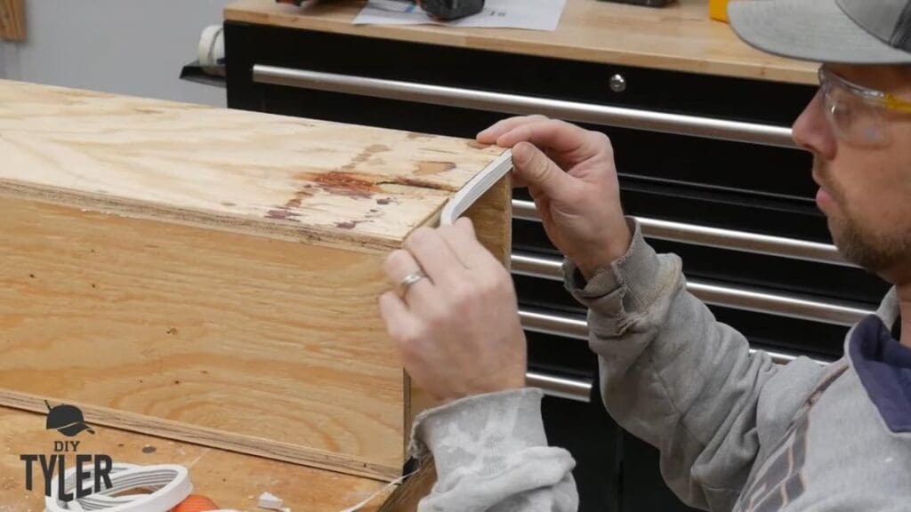 man applying weather stripping to end of steam box