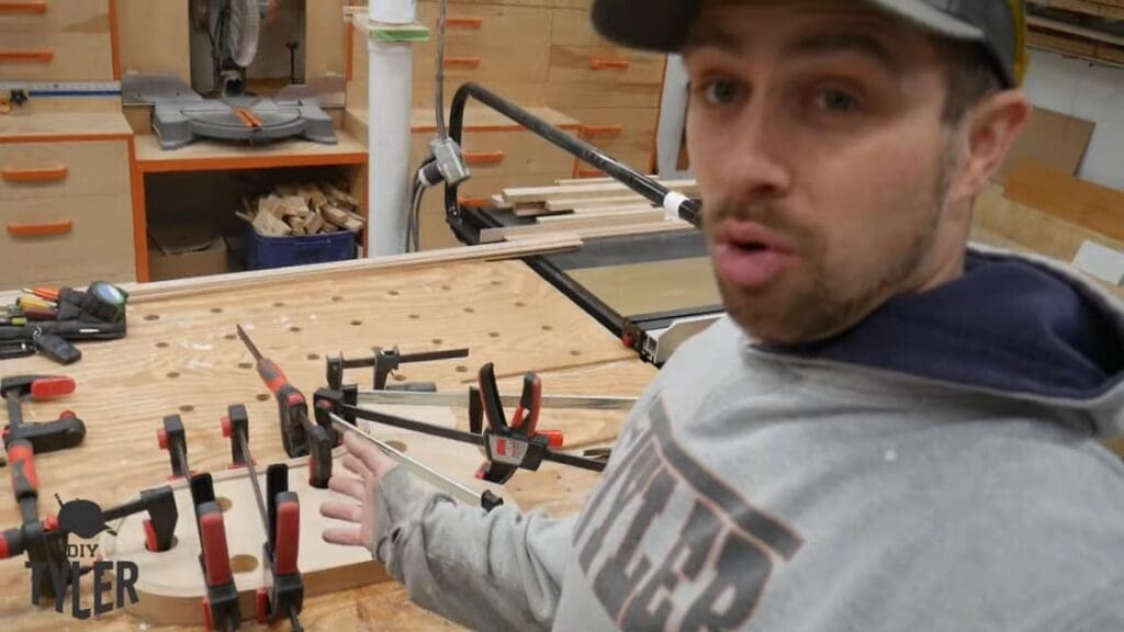 man gesturing to bent steam-treated wood fastened onto mold with clamps