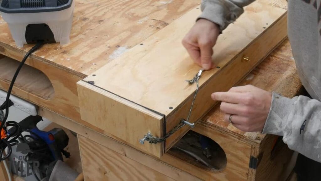 man tying paracord around bolts and docking cleat on steam box